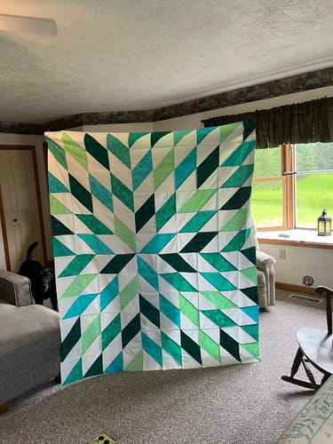 Customer's completed Nexus in Teal quilt featuring a geometric starburst pattern in various shades of green and teal.