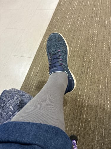 Reviewer's Eucalyptus Lyocell Compression Socks worn with a blue sneaker on a textured floor.