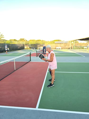 Reviewer standing on a pickleball court wearing CUURT Muuv court shoes while holding a paddle.