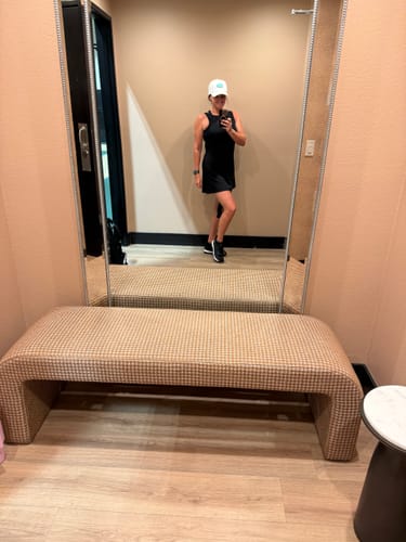 Reviewer in a mirror selfie wearing black CUURT Muuv court shoes with a black dress and white cap in a room.
