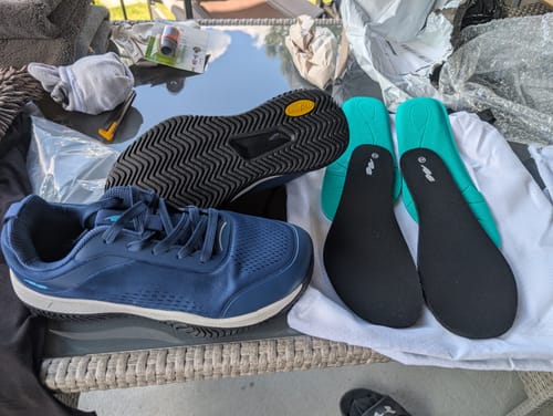 Customer's blue CUURT Muuv court shoes, showing the durable treaded sole, two teal inserts, and a white storage bag.