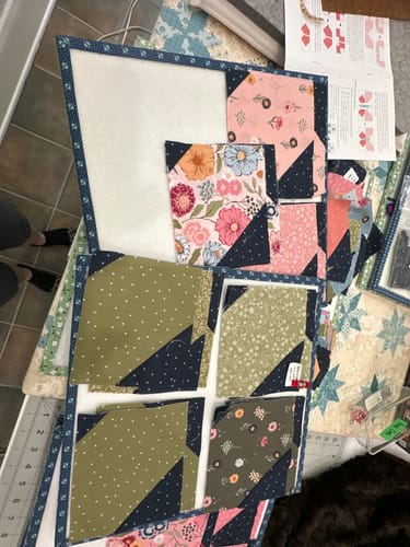 Customer's Flutter quilt kit pieces laid out on a workspace, featuring floral fabric blocks and butterfly patterns.