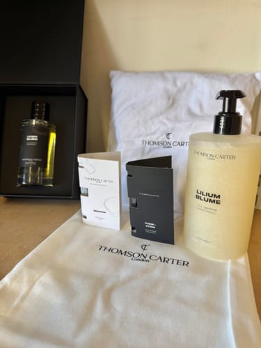 Customer's Lilium Blume body wash bottle, perfume, and white pillow packaging.