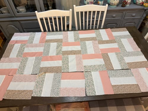 Customer's Picket Fences quilt kit pieces laid out on a dining table, showcasing a neutral color palette.