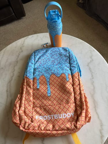 Customer's Blue Ice Cream Bottle Buddy sitting on a round table next to a matching patterned backpack.