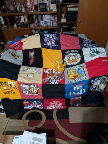Customer's Project Repat T-Shirt Quilt featuring various colorful squares, with a small stuffed animal sitting on top.