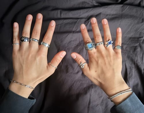 Customer's hands wearing multiple silver-tone rings from the 7 Piece Jewellery Bundle, showing various metal designs.