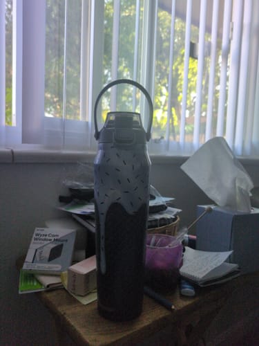 Customer's Mystery Bottle Buddy with a grey and black design, sitting on a bedside table.