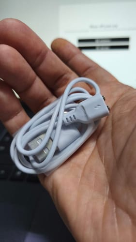 Customer's hand holding a coiled white Lem Magnetic Charging Cable.