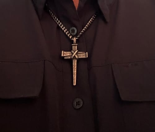 Customer's Nailed to the Cross necklace worn on a dark shirt, showing the heavy, antiqued silver-tone metal cross.