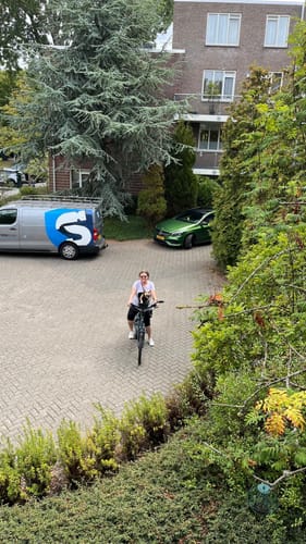Customer's Kvisp Dog Bike Carrier mounted on a bicycle with a person riding it through a paved courtyard.
