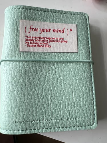 Customer's light green Free Your Mind pocket notebook with a tactile leather texture and a paper quote label attached.
