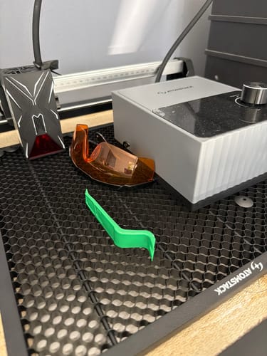 Reviewer's AtomStack Swift laser engraver parts, including the laser head, orange safety glasses, and honeycomb board.