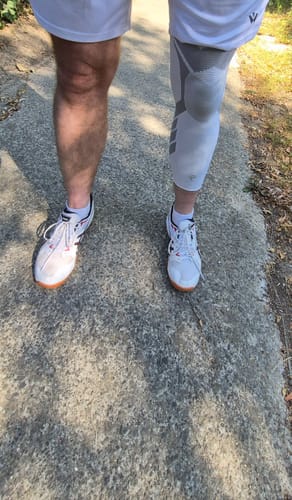 Reviewer's Maintien de compression V2 pour Genoux et Jambes, un genou nu et l'autre portant la genouillère blanche.