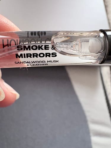 Customer's hand holding a clear, labeled 2ml Smoke & Mirrors fragrance sample vial.