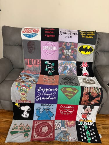 Customer's Project Repat T-Shirt Quilt featuring various colorful graphic t-shirt squares draped on a sofa.