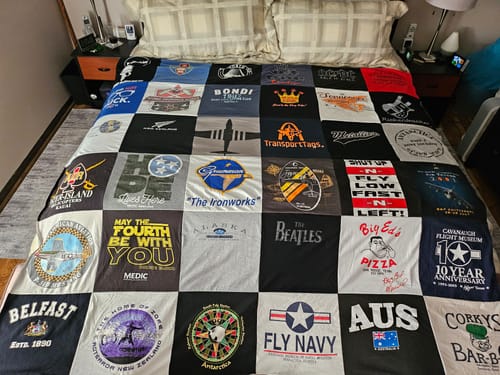 Customer's custom Project Repat T-Shirt Quilt featuring various graphic panels spread across a bed.