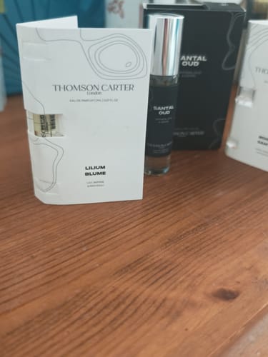 Customer's Lilium Blume Eau de Parfum sample card and Santal Oud bottle sitting on a wooden surface.