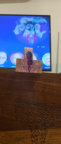 Customer's Artemis Bracelet card held in front of a television screen showing a film scene.