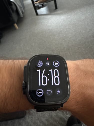Reviewer's Apple Watch Ultra 2 on their wrist, showing the bright digital watch face with activity and time metrics.