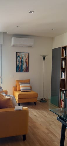 Customer's Anime in Danza painting hanging on a living room wall above a yellow armchair.