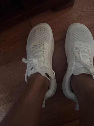 Customer's white CUURT Muuv court shoes being worn on wooden floor, showing a wide, spacious toe box design.