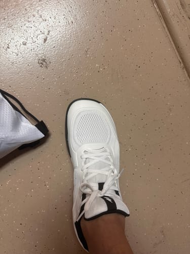 Customer's foot wearing a white Extra Comfort Support Insole shoe on a textured floor.