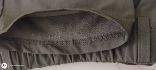 Customer's Dark Olive Power Stretch All Mode Pant close-up, showing frayed threads at the pant hem.