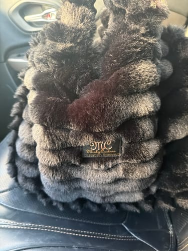 Customer's Annie Bag in ripple black, showing the soft, textured faux fur and brand logo tag close-up.