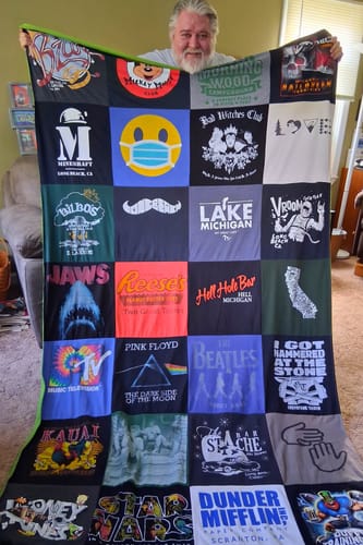 Customer's Project Repat T-Shirt Quilt held up, showing a patchwork of various colorful graphic tees.