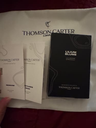 Customer's Lilium Blume perfume box and informational cards on a branded white dust bag.