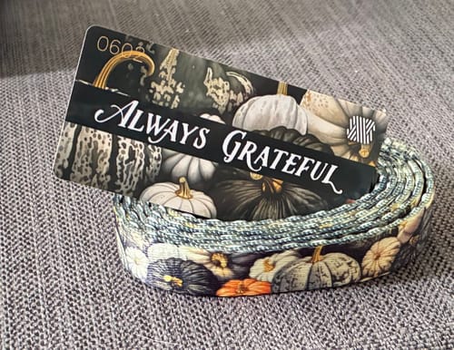 Customer's Always Grateful string featuring a pumpkin print, resting on a gray textured surface.