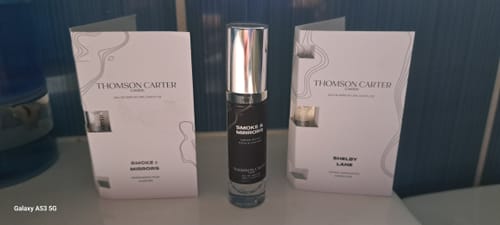 Customer's Smoke & Mirrors Eau de Parfum bottle standing between two white branded sample brochures.