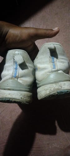 Customer's Bacca Bucci Essential shoes held in hand, showing back view of worn light-colored outsoles.
