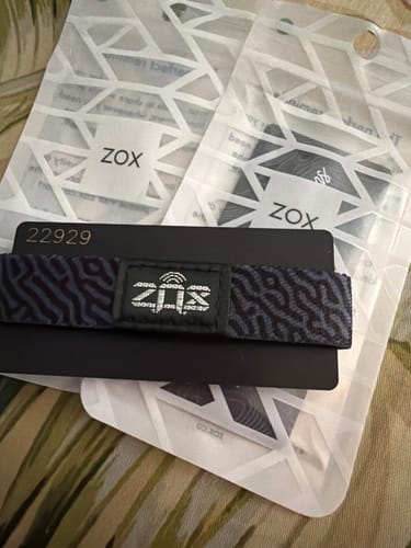 Customer's Cast Your Cares On Him Bible Verse bracelet resting on its product card with two ZOX packaging pouches.