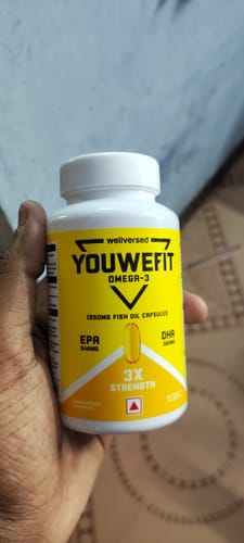 Customer's hand holding a white bottle of YouWeFit Omega-3 Fish Oil, highlighting the yellow label with product details.