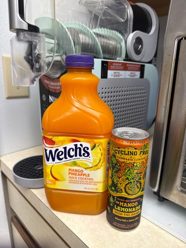 Customer's Sparkling THC Mango Lemonade can next to a juice bottle on a counter, ready for a Ninja Slushi.