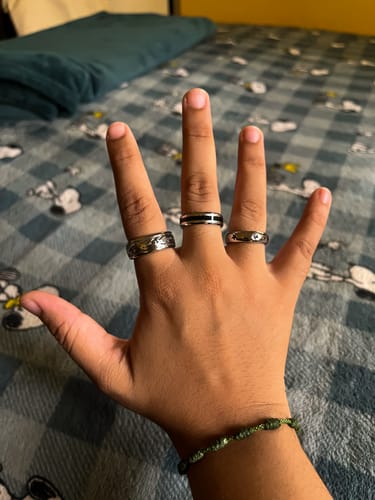 Customer's Stars Ring worn on three fingers on their hand, resting against a patterned blanket.