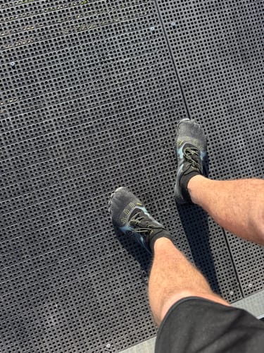 Customer's Fast Ⅰ barefoot shoes on person's feet, standing on a textured black surface.