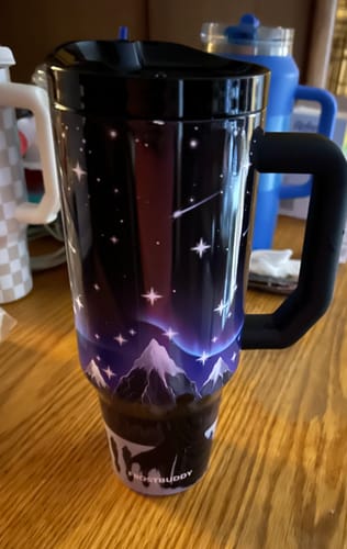 Customer's Thicc Buddy 40oz mug in Nightfall print with mountain design on a table.