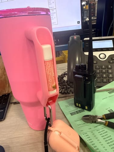 Reviewer's pink Thicc Buddy mug on a desk with a lip balm held in the handle's built-in holder.