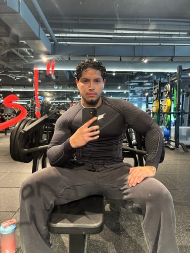 Reviewer wearing a black Batman compression longsleeve in a gym, highlighting the textured, fitted fabric.