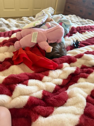 Customer's Hugs Flag Blanket in red, white, and blue, draped on a bed with a plush toy resting on it.