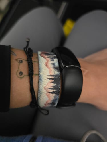 Customer's You're Almost There Bracelet worn on wrist alongside a black fitness band and another dark rope bracelet.