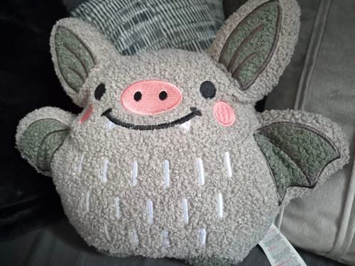 Customer's weiches Fledermaus Kissen Bouclé mit niedlichem Gesicht auf einem Sofa.