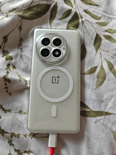 Customer's OnePlus 13 phone in a clear Anti Yellow Magsafe Case, charging on a leaf patterned surface.