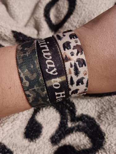 Customer's wrist wearing three decorative fabric bracelets, featuring the Stairway To Heaven text on one.