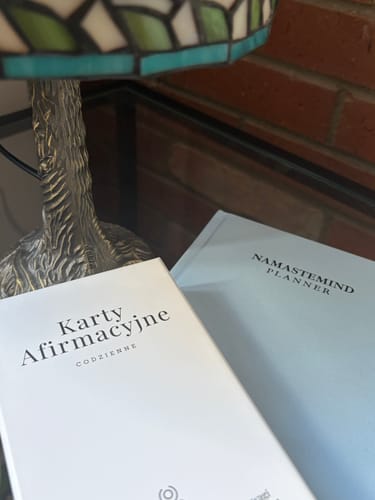 Customer's Namastemind Planner and affirmation cards on a table near a glowing lamp.