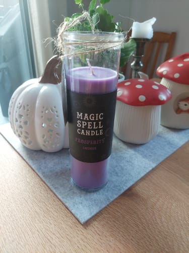 Kundenfoto der lila Wohlstand Ritualkerze Lavendel auf einer grauen Unterlage zwischen Dekoration.