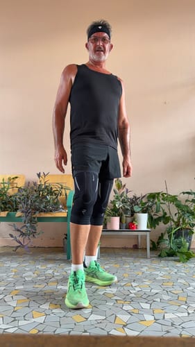 Customer wearing NEOTEX™ de course knee sleeves over black athletic shorts in a home setting.